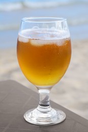Cold beer in glass on beach, closeup