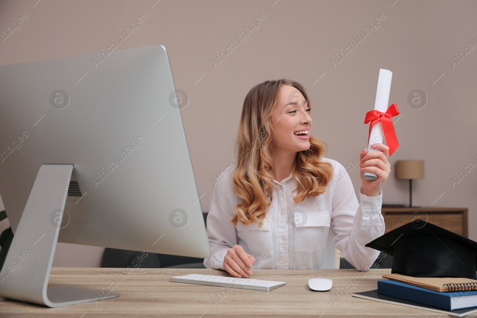 Photo of Happy student with graduation hat and diploma at workplace in office