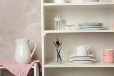 White shelving unit with set of dishware near wall