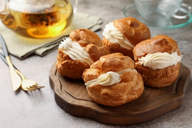 Photo of Delicious profiteroles filled with cream on grey table