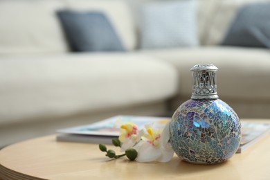 Photo of Stylish catalytic lamp with orchid on wooden table in living room, space for text. Cozy interior