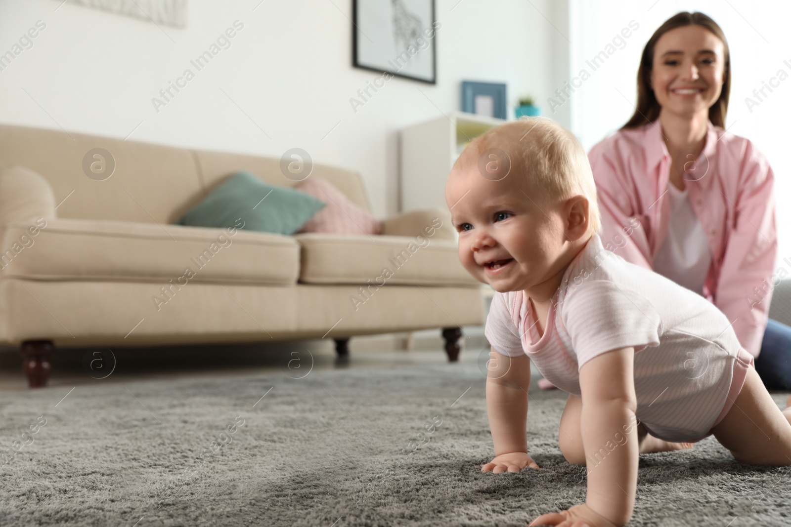 Photo of Adorable little baby crawling near mother at home