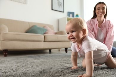 Adorable little baby crawling near mother at home