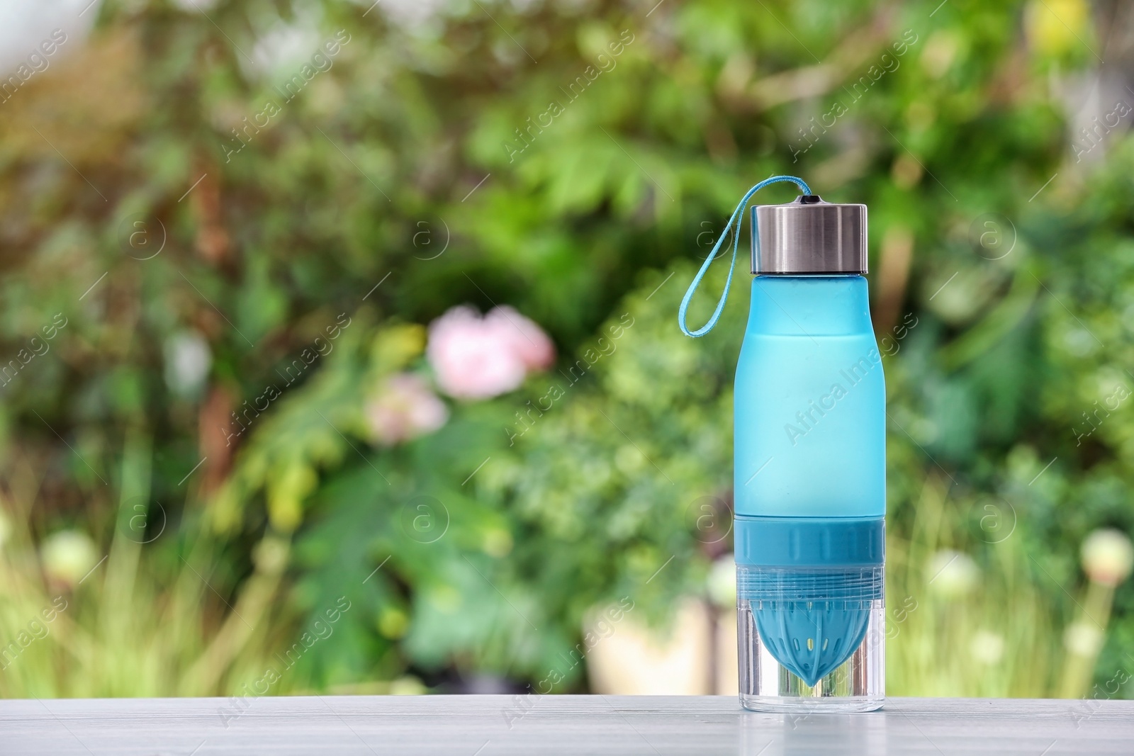 Photo of Sports water bottle on table against blurred background. Space for text