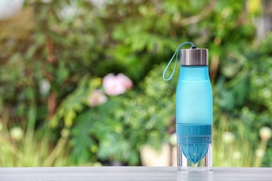 Photo of Sports water bottle on table against blurred background. Space for text