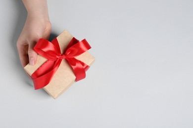 Photo of Woman holding gift box with red bow on white background, above view. Space for text