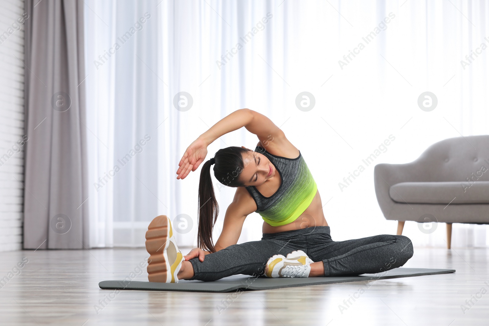 Photo of Young woman in fitness clothes doing exercise at home