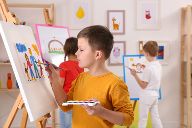 Photo of Cute little child painting during lesson in room