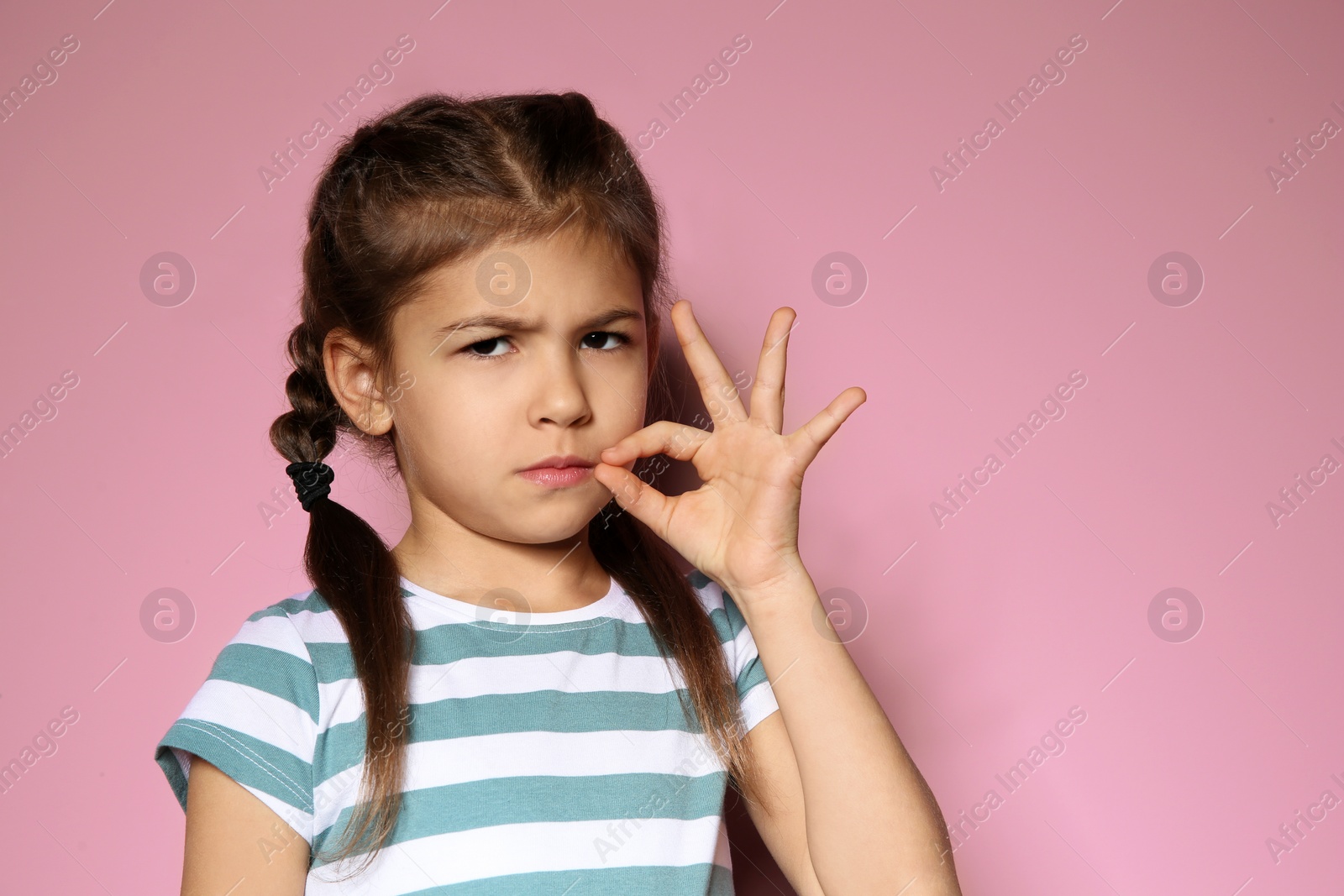 Photo of Little girl zipping her mouth on color background, space for text. Using sign language