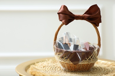 Photo of Gift set in wicker basket on golden table near white wall. Space for text