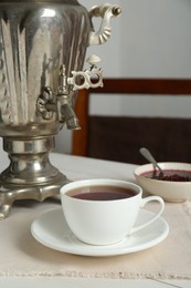 Photo of Vintage samovar and cuphot drink served on white wooden table. Traditional Russian tea ceremony