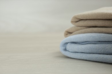 Photo of Cashmere clothes on wooden table, closeup. Space for text