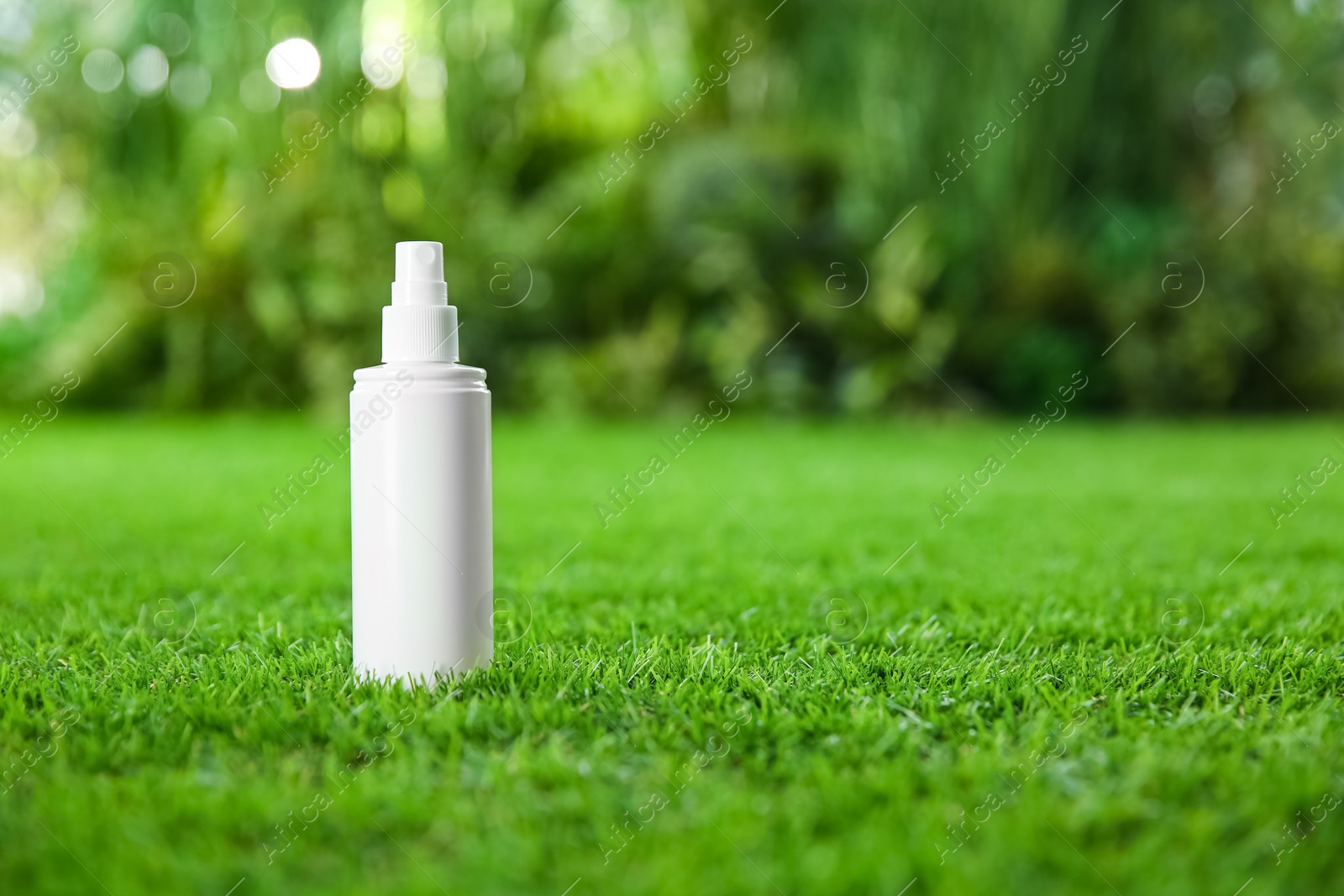 Photo of Bottle of insect repellent spray on green grass. Space for text