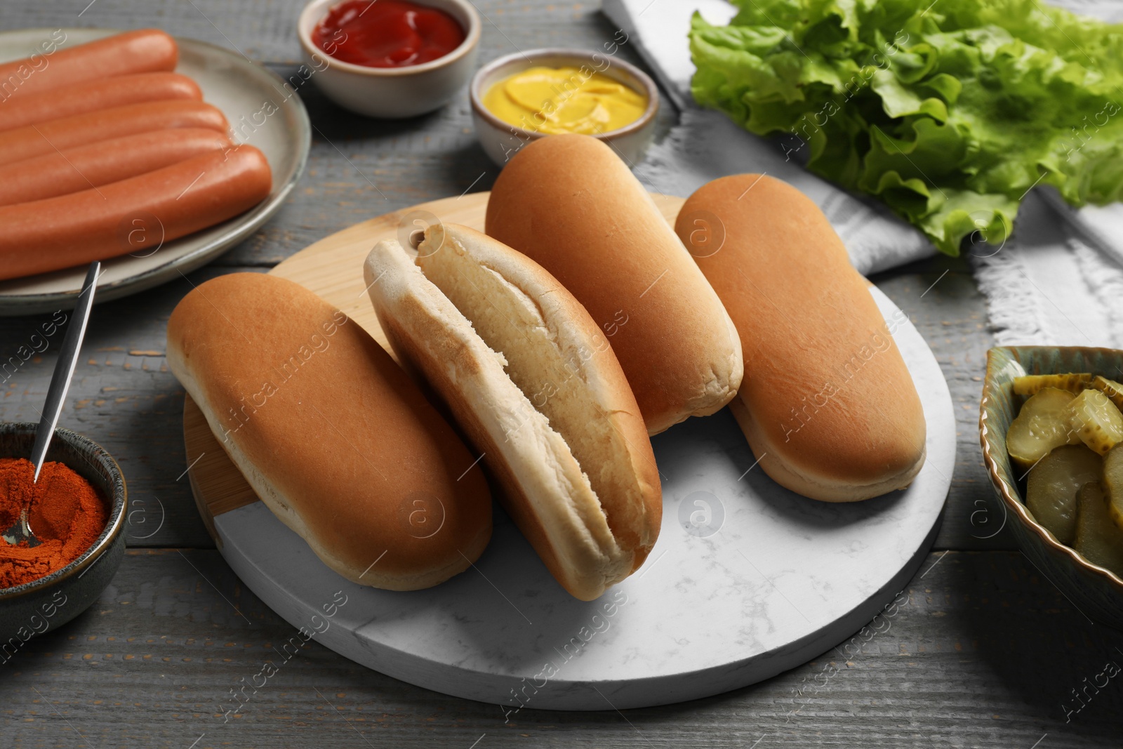 Photo of Different tasty ingredients for hot dog on light grey wooden table
