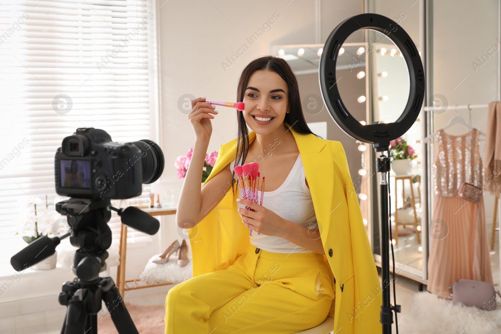 Photo of Blogger with brushes recording video in dressing room at home. Using ring lamp and camera