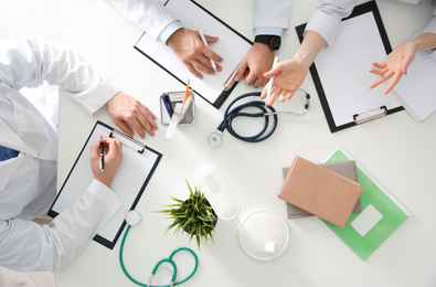 Doctors having meeting at table in office, top view