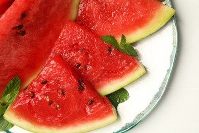 Photo of Plate with slices of juicy watermelon on white table, closeup