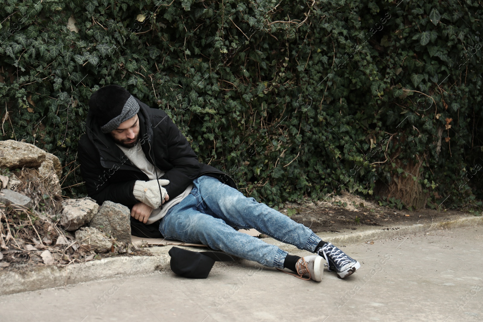 Photo of Poor homeless man lying on street in city