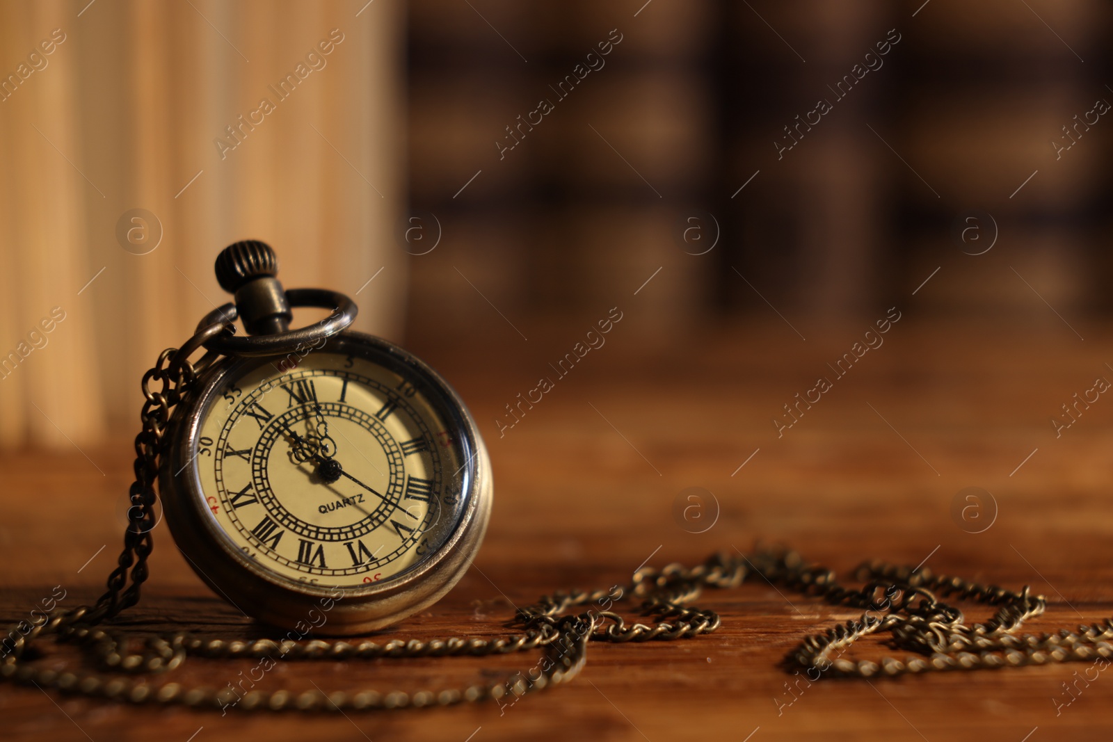 Photo of Pocket clock with chain on wooden table, closeup. Space for text