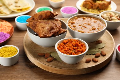Traditional Indian food and color powders on wooden table, closeup. Holi festival celebration