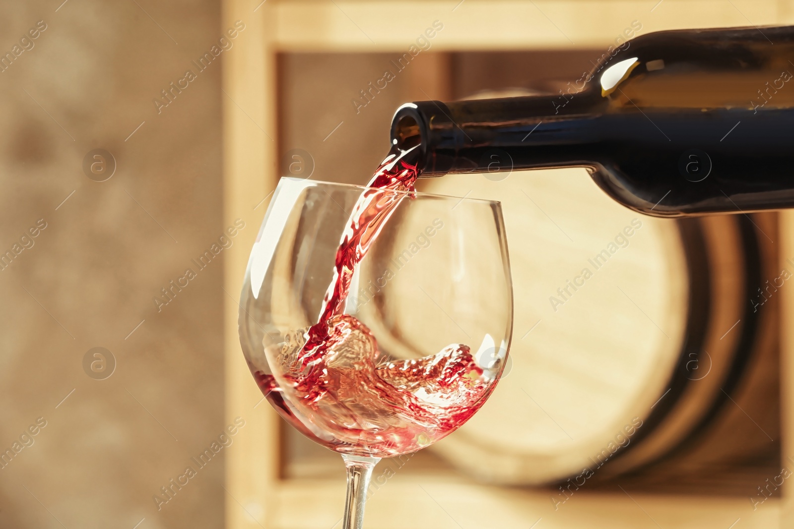 Photo of Pouring delicious red wine into glass on blurred background