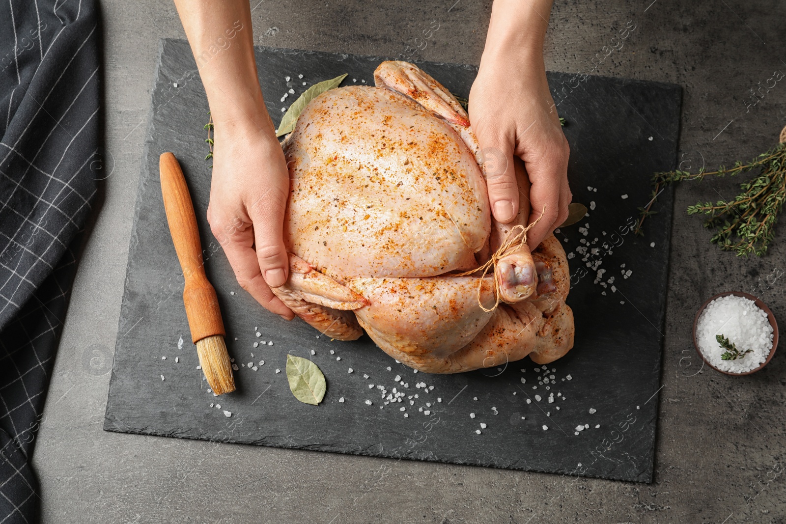 Photo of Woman preparing whole turkey at table, top view