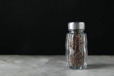 Photo of Pepper shaker on light textured table against black background. Space for text
