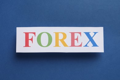 Photo of Sheet of paper with word Forex on dark blue background, top view