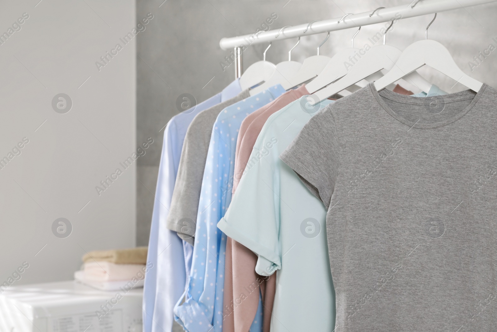 Photo of Different apparel hanging on clothes rack indoors, space for text