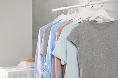 Photo of Different apparel hanging on clothes rack indoors, space for text