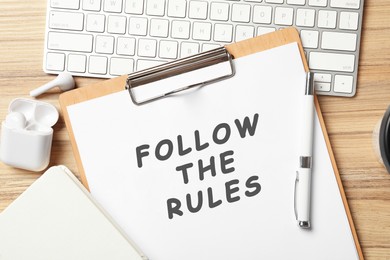 Paper with phrase Follow The Rules, stationery and computer keyboard on wooden table, flat lay