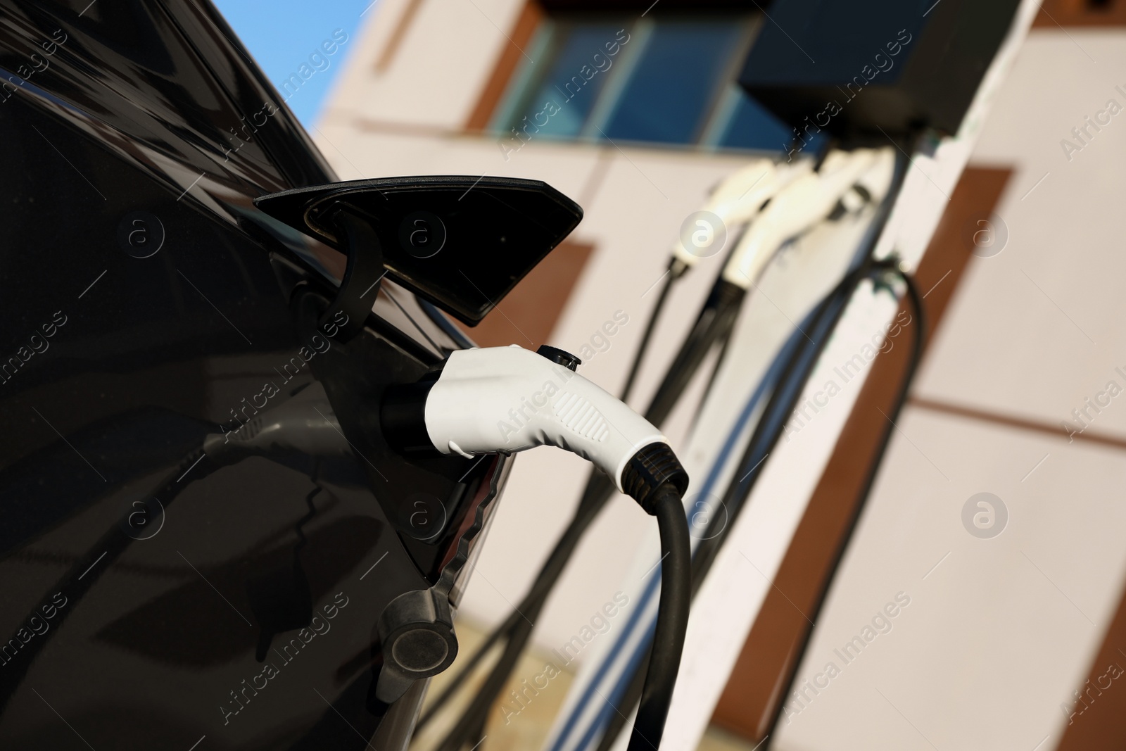 Photo of Charging modern electric car from station outdoors, closeup