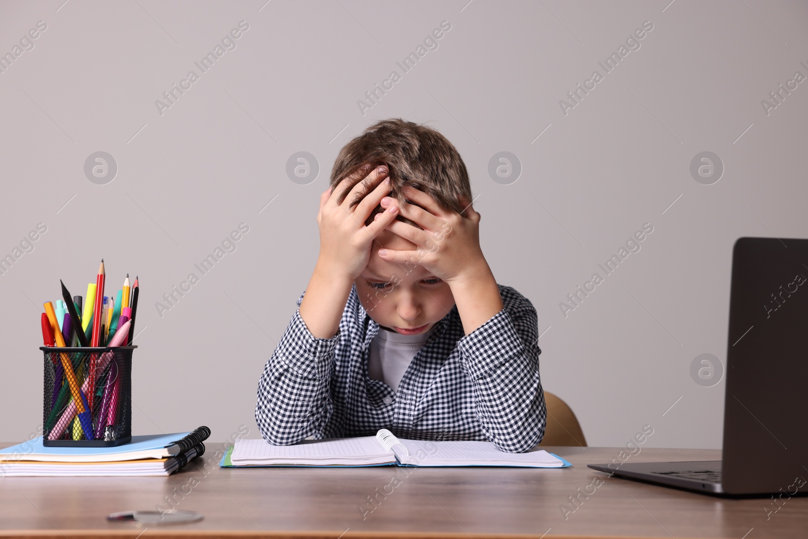 Photo of Little boy with stationery suffering from dyslexia at wooden table