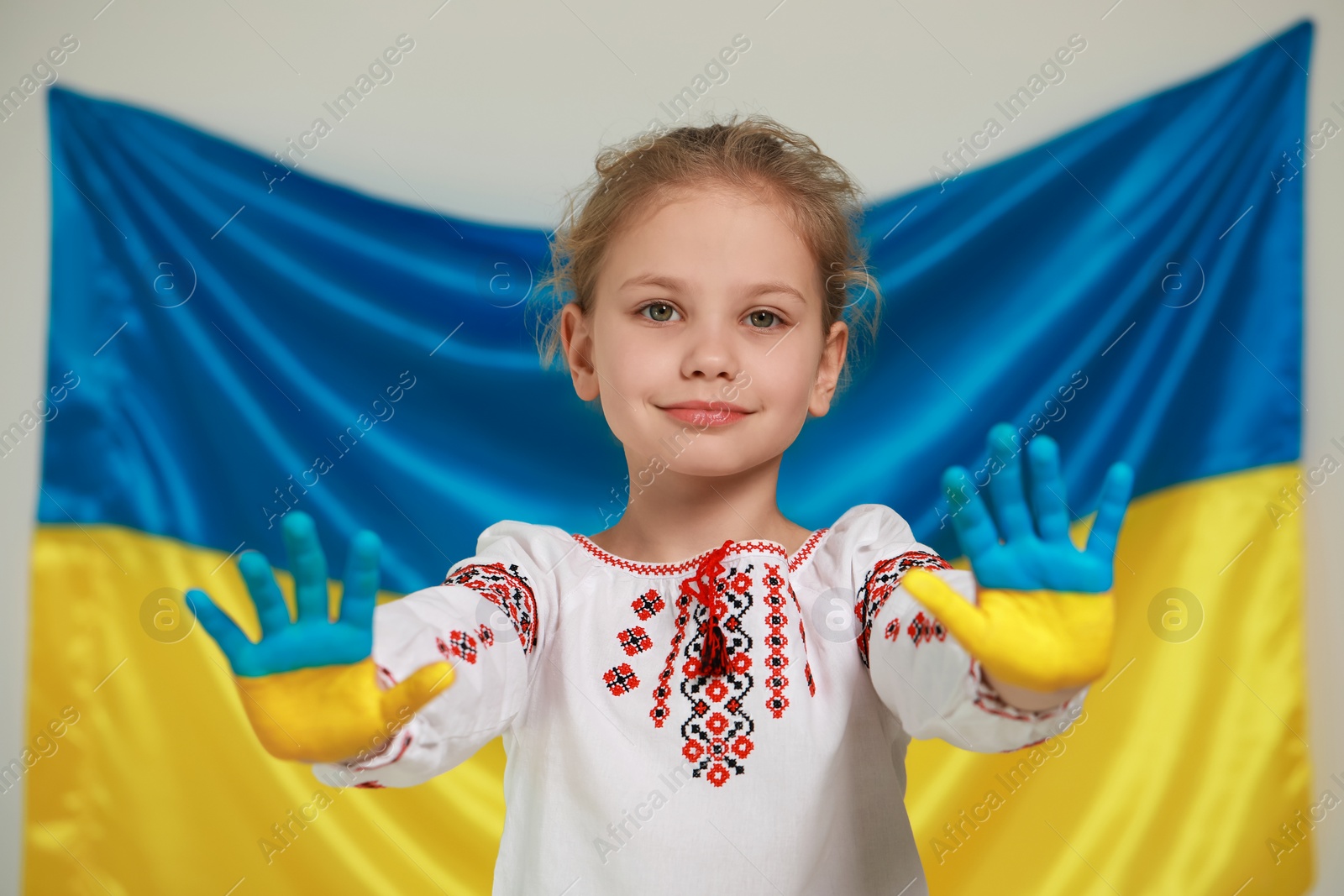 Photo of Little girl with painted hands near Ukrainian flag. Love Ukraine concept