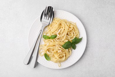 Photo of Delicious pasta with brie cheese and basil leaves on light grey table, top view