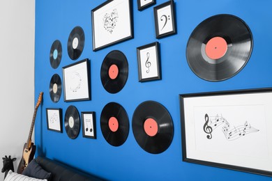 Vinyl records and different pictures on blue wall in living room