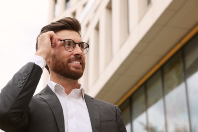Photo of Handsome bearded businessman in eyeglasses near building outdoors, space for text