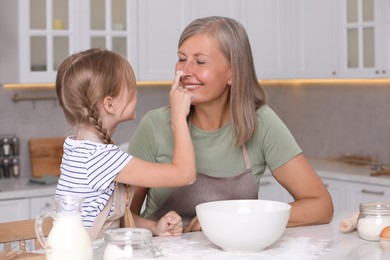 Photo of Happy grandmother with her granddaughter having fun while cooking together in kitchen