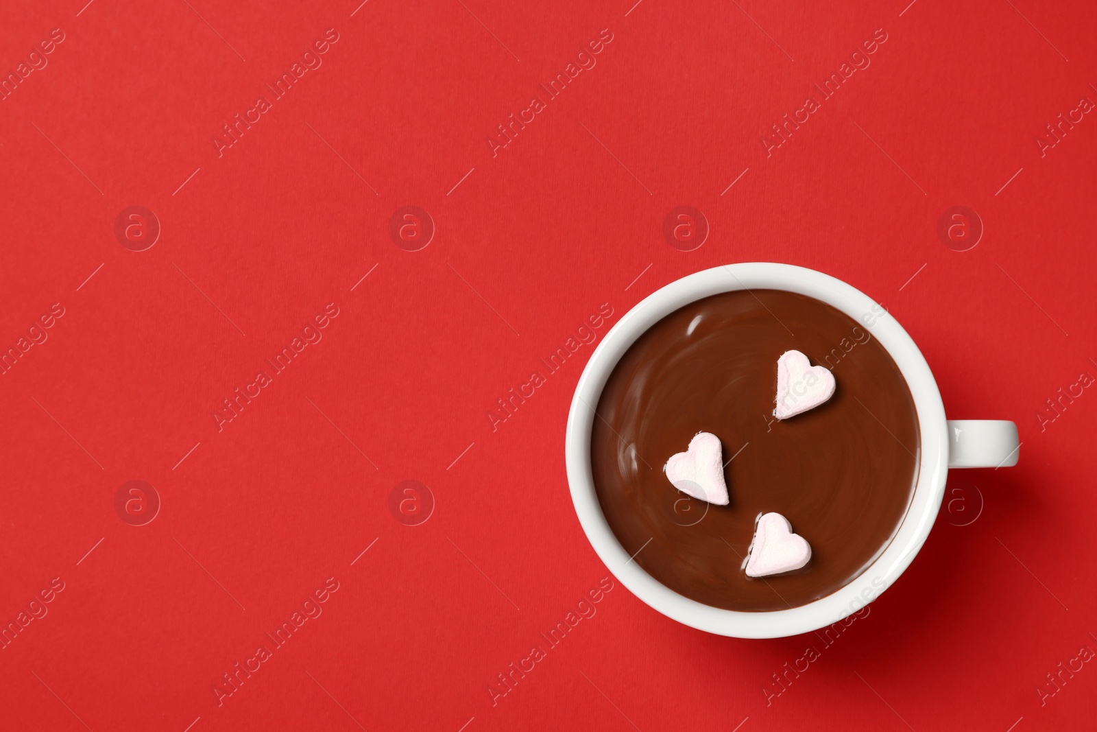 Photo of Cup of hot chocolate with heart shaped marshmallows on red background, top view. Space for text