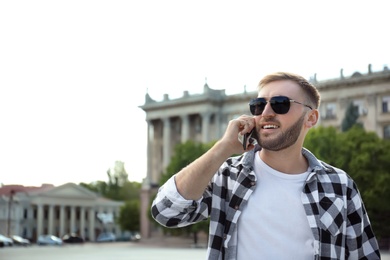 Photo of Young man talking on smartphone on city street