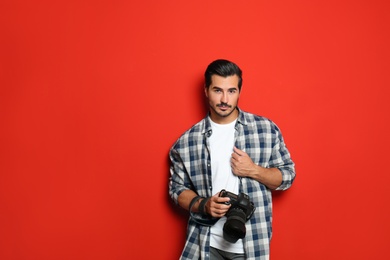 Photo of Young photographer with professional camera on red background. Space for text
