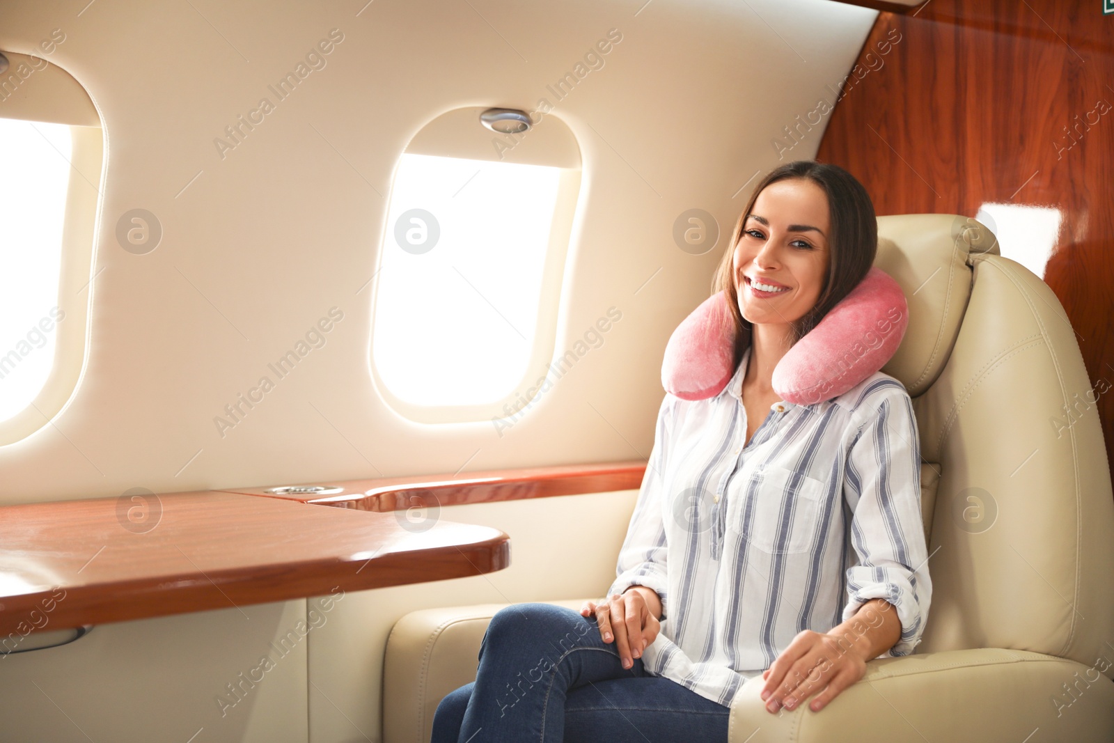 Image of Happy woman with neck pillow on plane