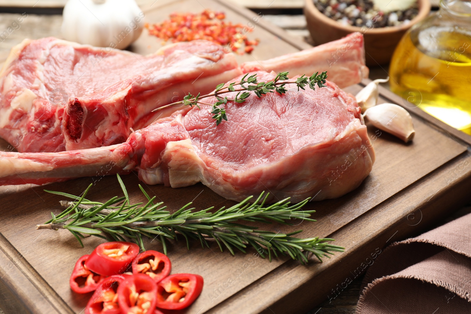 Photo of Fresh tomahawk beef cuts and spices on wooden board, closeup