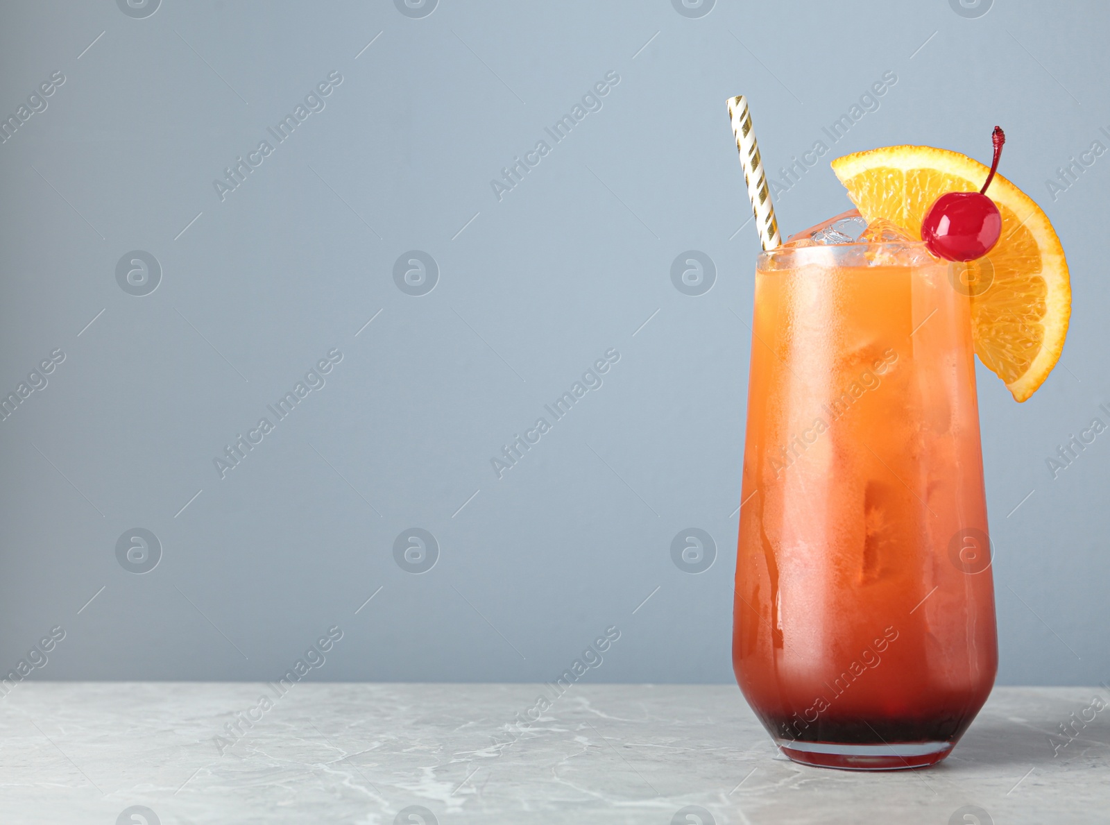 Photo of Tasty cocktail with ice cubes and orange on light marble table, closeup. Space for text