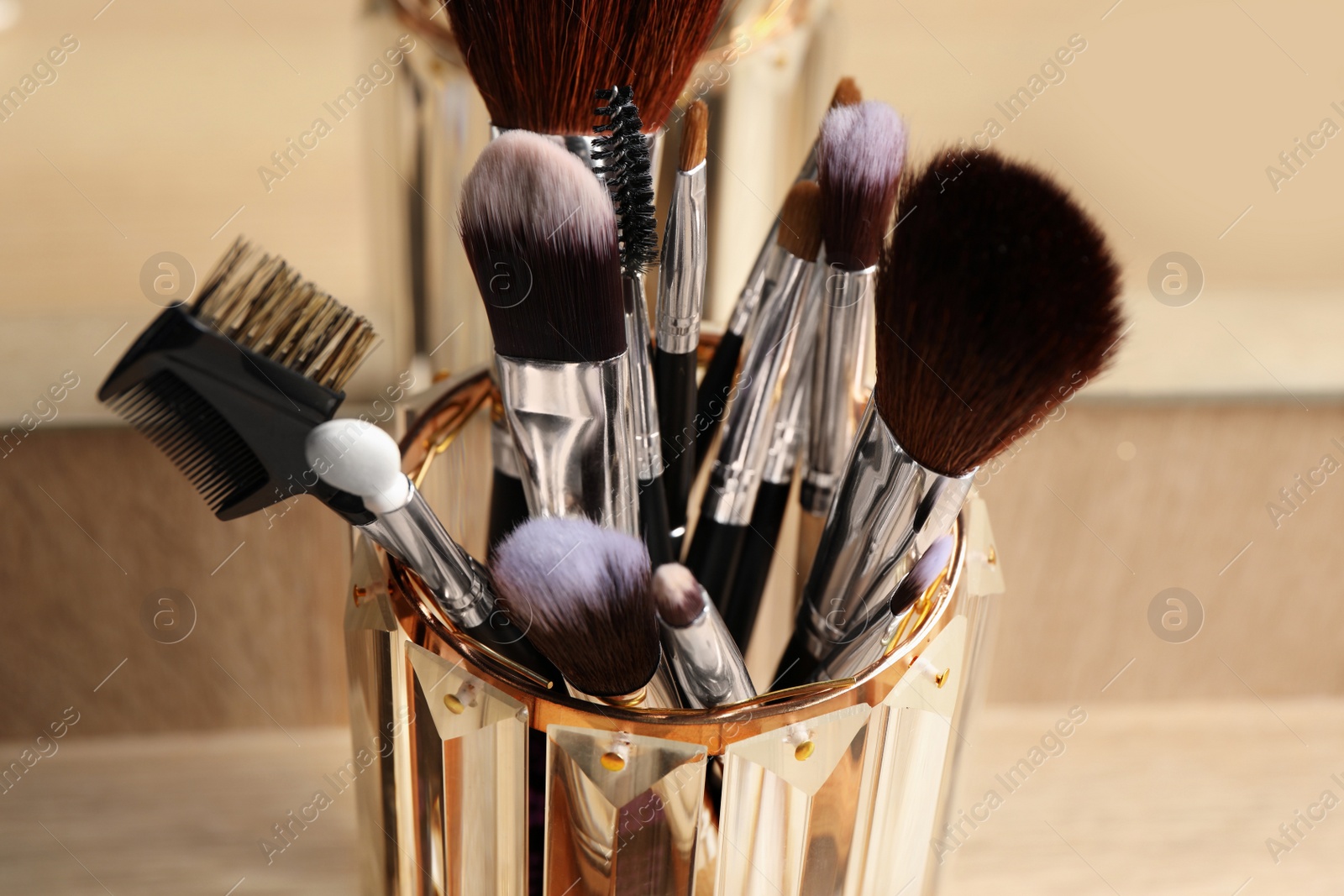 Photo of Set of professional makeup brushes near mirror on wooden table, closeup