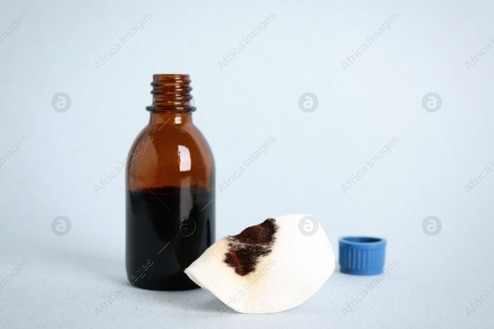 Photo of Bottle of medical iodine and cotton pad on light table, space for text