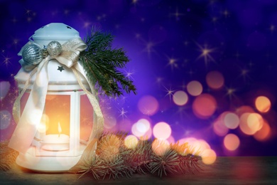 Image of Christmas lantern with burning candle on table, space for text. Magical atmosphere