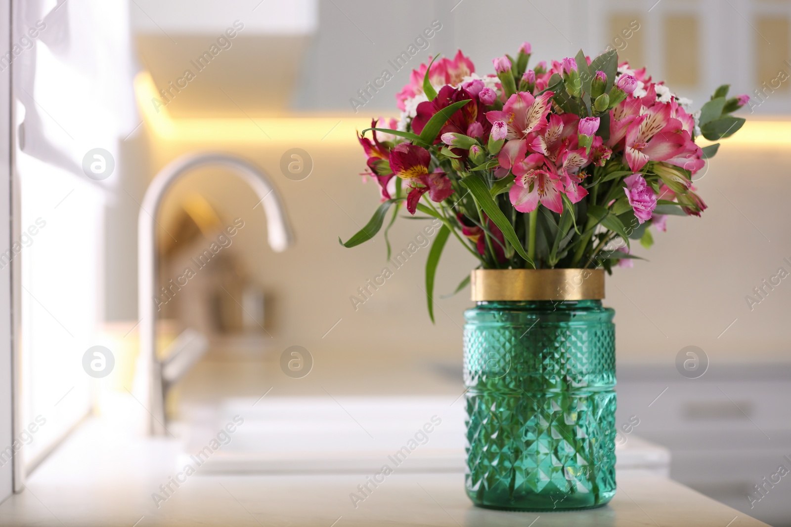 Photo of Vase with beautiful alstroemeria on countertop in kitchen, space for text. Interior design