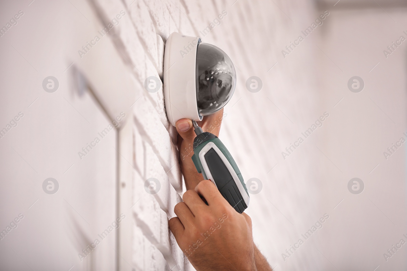 Photo of Technician installing CCTV camera on wall, closeup