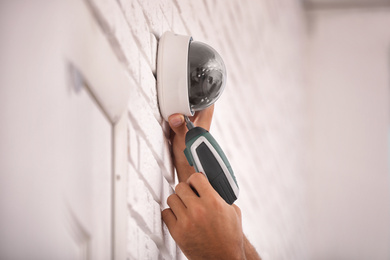 Photo of Technician installing CCTV camera on wall, closeup